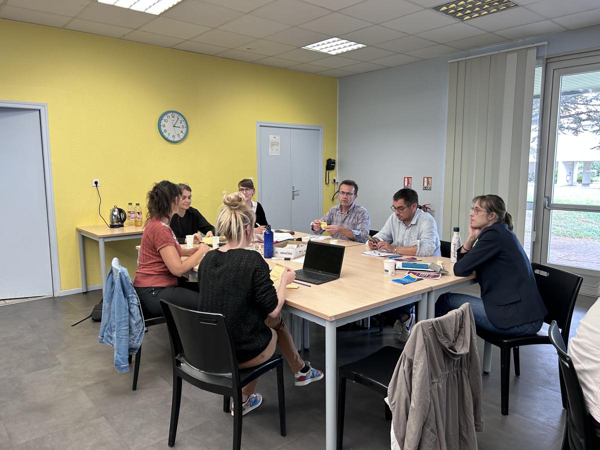 7 personnes sont assises autour d'une table et discutent.