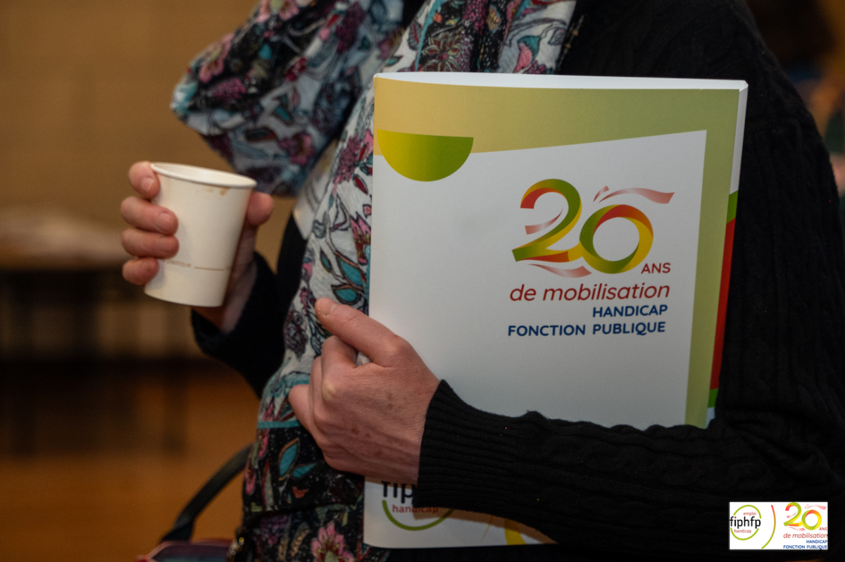 Participante tenant une pochette où il est écrit "20 ans de mobilisation handicap fonction publique