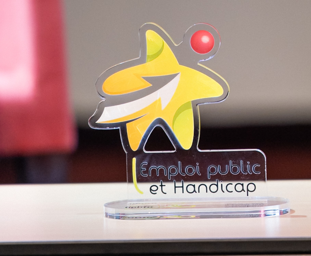 Trophée en verre Emploi public et handicap posé sur une table