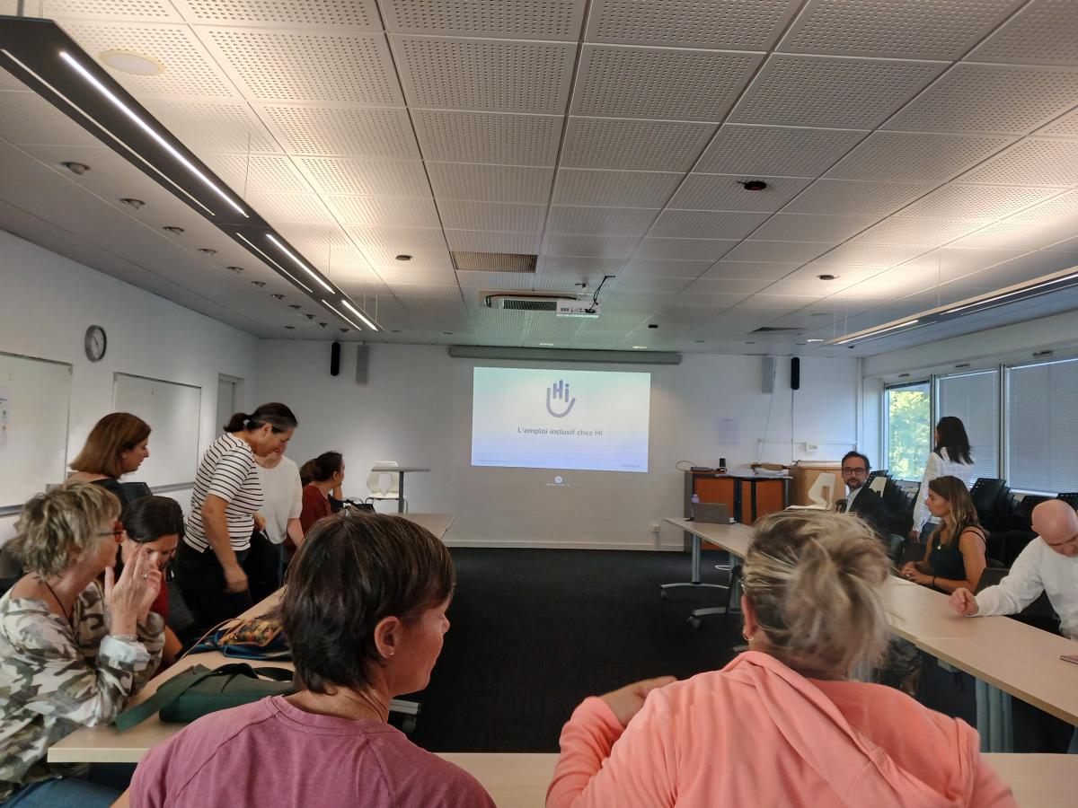 Plusieurs personnes dans une salle de réunion devant une présentation PowerPoint 